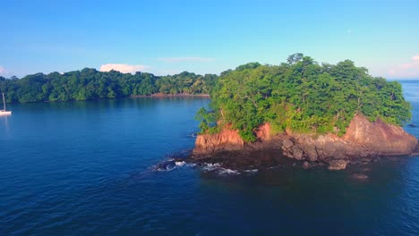 Sliding-past-a-tree-covered-outcropping-to-reveal-two-monohull-sailboats-in-a-calm-bay-in-the-Parida-Islands-in-Panama