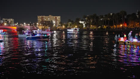 Pontoon-fishing-and-speed-boats-drive-along-waterway-at-night-in-festive-holiday-parade