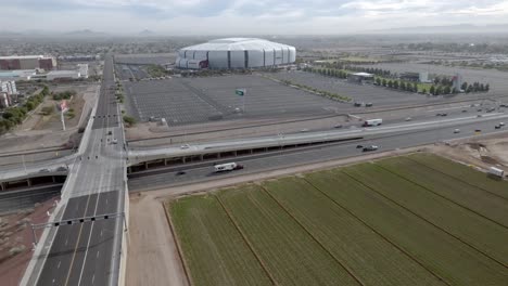 State-Farm-Stadium,-home-of-the-Arizona-Cardinals-National-Football-League-team-in-Glendale,-Arizona-with-freeway-traffic-drone-video-wide-shot-stable