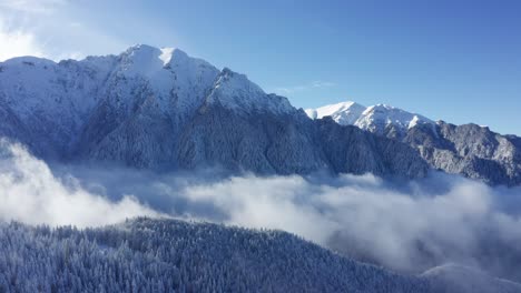 Schneebedeckte-Bucegi-Berge-Ragen-über-Den-Wolken-Auf,-Ruhige-Winterlandschaft