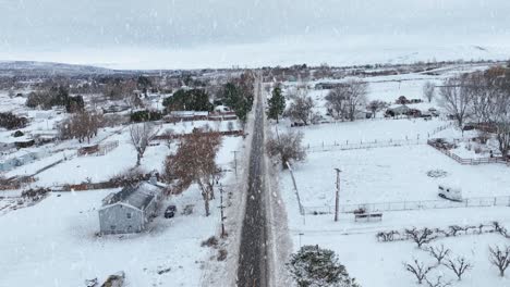 Toma-Aérea-De-Nieve-Cayendo-Sobre-Una-Carretera-Arada-En-El-Este-De-Washington.