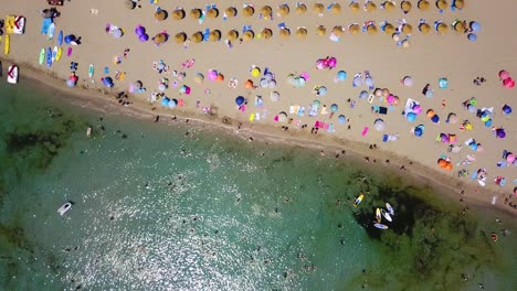 Retreating-drone-shot-above-the-beachfront-of-Playa-de-Canyamel,-a-popular-destination-located-in-the-island-of-Mallorca,-Spain