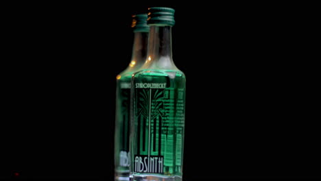 Staroplzenecky-Absinthe-Bottles,-Strong-Alcoholic-Drink-Spinning-Close-Up,-Black-Background