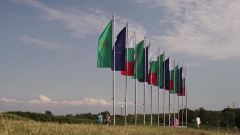 Turistas-Y-Visitantes-Caminando-Por-Una-Fila-De-Banderas-Fuera-Del-Monumento-Estatal-Búlgaro