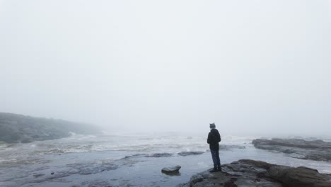 Young-boy-standing-on-the-rocks-on-a-coastal-landscape