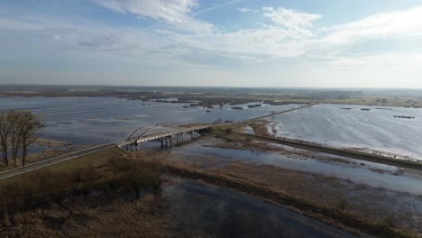 Totale-Luftaufnahme-überflutetes-Gebiet-Wasser-Fluss-Überlauf-Brücke-Straße-Sonnig