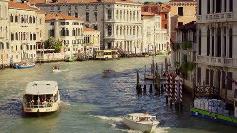 Taxi-boat-on-the-water-of-Canal-Grande-in-Venice,-Italy,-is-cruising-under-a-bridge-in-the-morning-sunlight