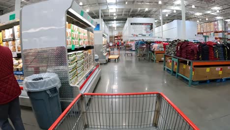 POV---Slowly-pushing-cart-between-the-refrigerated-cases-and-tables-of-clothing-displays-at-local-Costco