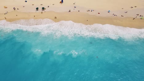 Myrtos-beach-with-turquoise-waters-and-sunbathers-on-the-golden-sands,-kefalonia,-aerial-view