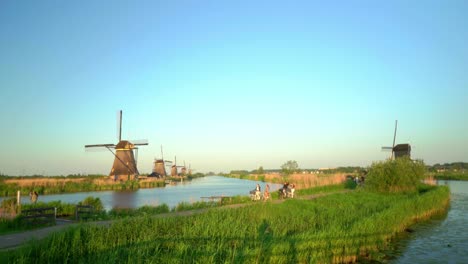 Tourists-bike-through-Kinderdijk-Dutch-traditional-windmill-landscape