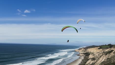 Para-gliders-flying-along-the-coast-line-with-cliffs-on-a-beautiful-day-at-Torrey-Pines-Gliderport-in-La-Jolla,-California