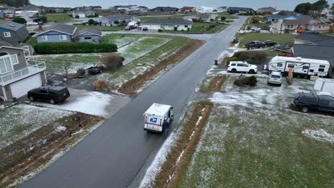 Drone-shot-orbiting-a-USPS-delivery-vehicle-in-snow,-man-opening-trunk