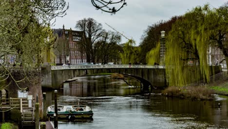 Time-lapse-of-people-and-cars-crossing-bridge-over-river-in-Den-Bosch,-the-Netherlands---zoom-out