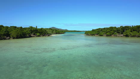 Low-flyover-above-shallow-Isle-of-Pines-channel,-Pic-N’ga-in-background