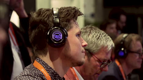 Man-wearing-silent-disco-headphones-during-a-conference-listening-to-the-speaker