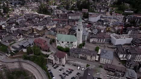 Cortina-D'Ampezzo-historic-church-aerial-toward,-Dolomites-Italy