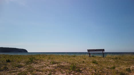 Lone-bench-overlooking-the-sea-on-Gotland's-Irevik,-clear-sky,-daytime