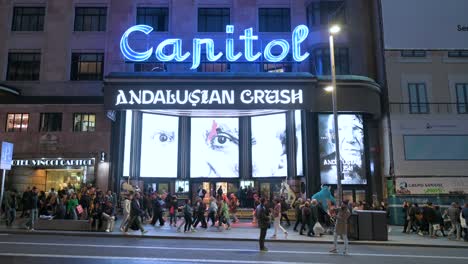 Capitol-Theater-and-cinema-entrance-at-Gran-Via-Street,-known-for-its-numerous-entertainment-offerings-of-restaurants,-bars,-clothing-stores,-cinemas,-and-theatres,-seen-during-nighttime-in-Madrid