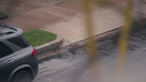 Día-Lluvioso-En-La-Ciudad,-Movimiento-Lento-De-Gotas-De-Lluvia-Cayendo-Sobre-La-Calle,-Acera-Y-Drenaje