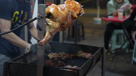 Large-spit-roast-with-joint-of-meat-on-over-coal-barbecue-with-man-cooking