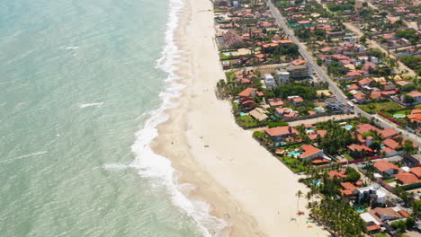 Aerial-view-of-the-sea,-waves-and-the-city-around,-Cumbuco,-Ceara,-Brazil