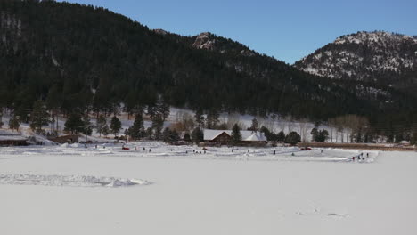 Ice-skating-skate-hockey-rink-lake-pond-hockey-winter-Etown-Evergreen-Lake-house-Denver-golf-course-Colorado-aerial-cinematic-drone-sunny-bluesky-morning-winter-fresh-snow-slowly-forward-up-movement