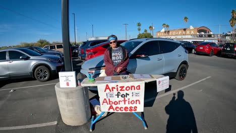 Volunteer-standing-at-table-representing-the-Arizona-for-Abortion-Access-which-is-a-coalition-of-of-reproductive-health,-rights,-and-justice-organizations