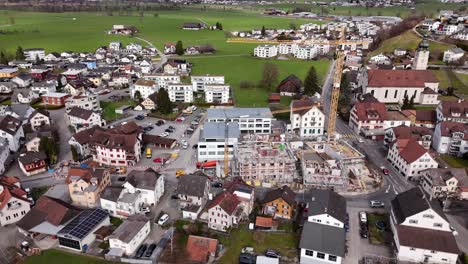 Aerial-orbit-of-crane-working-at-construction-site-in-center-of-small-swiss-village