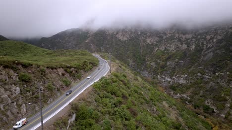 Santa-Monica-Mountains-in-Malibu,-California-on-a-cloudy-day-with-traffic-driving-on-road-and-drone-video-stable