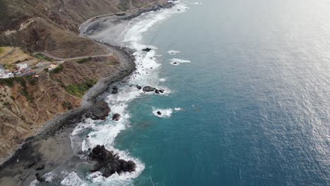 Aerial-view-of-a-black-sand-beach-at-sunset