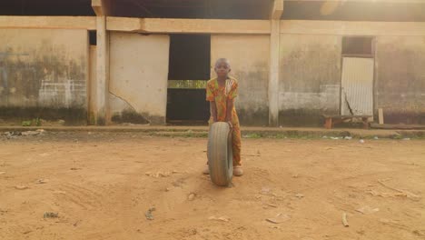 Black-young-boy-from-madagascar-rolls-car-tire-in-the-street-as-a-game-for-fun