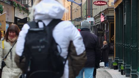 People-walking-on-Vasterlanggatan-in-Stockholm's-Old-Town,-lined-with-shops-and-tourists