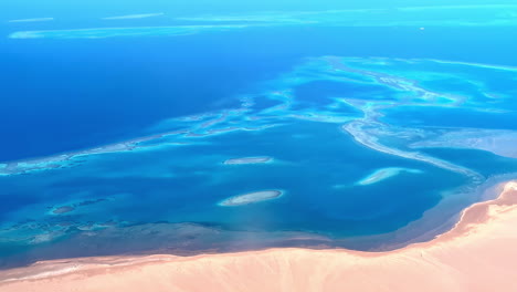 Aerial-drone-shot-flying-high-over-brown-desert-alongside-blue-sea-in-Ras-Mohamed-Nature-Reserve,-Egypt-at-daytime