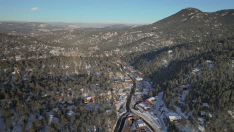 Downtown-old-historic-Evergreen-Colorado-Denver-aerial-drone-cinematic-fresh-snow-dusting-cold-white-scenic-landscape-dam-lake-traffic-driving-around-house-front-range-sunset-bluesky-forward-motion