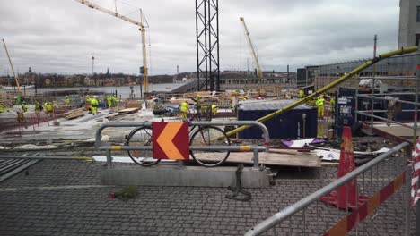 Yellow-dressed-workers-move-around-at-construction-site-on-cloudy-day-in-Stockholm