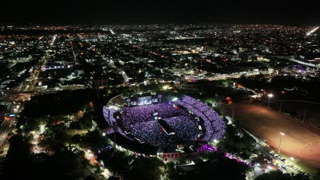 Musical-festival-with-celebrating-crowd-of-people-in-open-air-stadium-at-night