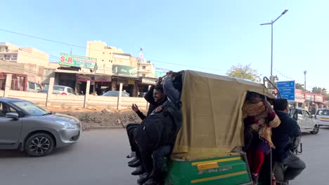 An-auto-rickshaw-on-the-road-full-of-people-beyond-its-seating-capacity-hanging-outside-from-the-vehicle-near-Sikanderpur-metro-station