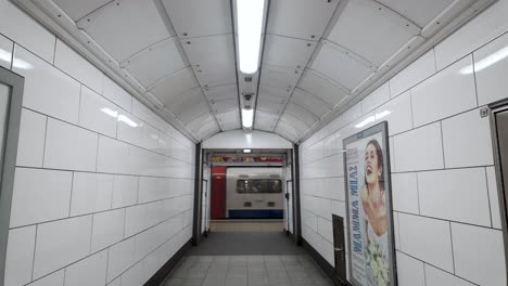 A-Bakerloo-Line-train-pulls-into-the-platform-at-Oxford-Street-Station-in-London,-England,-viewed-from-the-corridor-sidewalk,-the-concept-of-urban-connectivity-and-seamless-transportation-integration