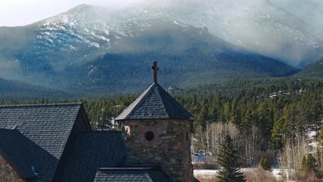 Simple-elegant-cross-on-top-of-old-chapel-in-rocky-mountains-of-Allenspark-Colorado,-telephoto-parallax