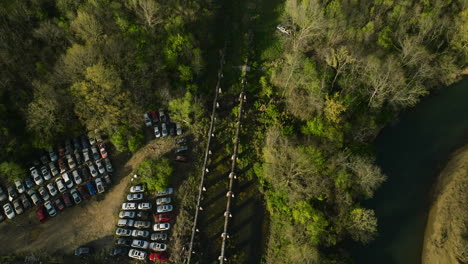 A-junkyard-with-rows-of-cars-near-a-forest-in-fayetteville,-ar,-daylight,-aerial-view