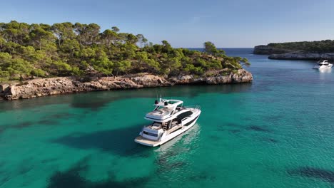 Drone-shot-of-luxury-yacht-anchored-in-crystal-clear-turqoise-waters-of-mediterranean-bay