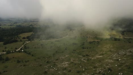 Aerial-View-of-Velebit-National-Park:-Flying-Through-Clouds-Park-with-Gravel-Road-and-Trees-in-Croatia