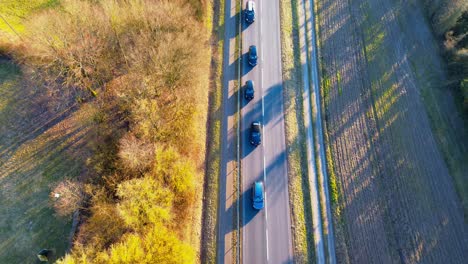 Vogelperspektive-Von-Fahrzeugen-Auf-Einer-Landstraße,-Die-In-Der-Dämmerung-Lange-Schatten-Werfen