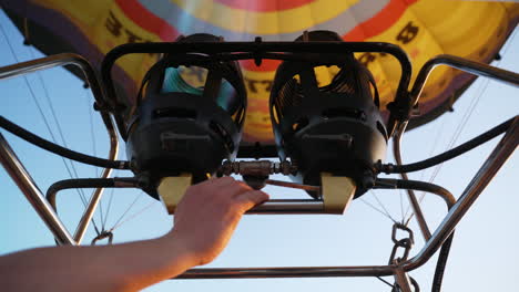 Operator-filling-colourful-hot-air-balloon-with-propane-gas-flames-preparing-for-take-off