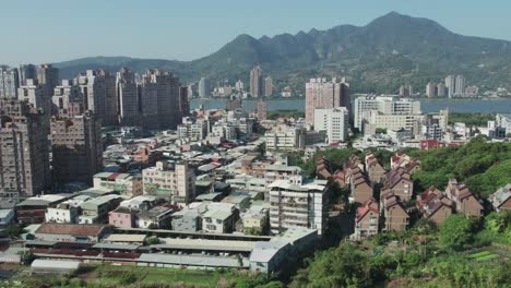 Bright-daytime-view-of-Zhuwei,-Tamsui-district-with-Taipei-mountains-in-the-background,-Establishing-Shot