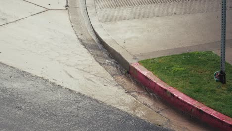 Cámara-Lenta-Sobre-El-Agua-De-Lluvia-Que-Fluye-Por-La-Calle-Y-El-Drenaje