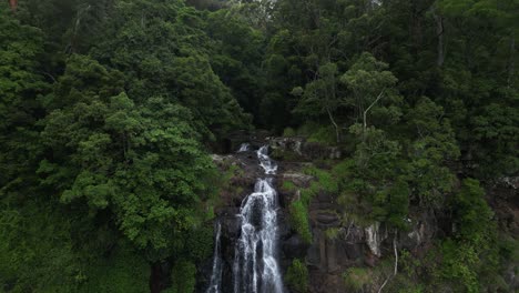 A-hidden-rainforest-stream-cascading-down-a-waterfall-surrounded-by-a-misty-fog