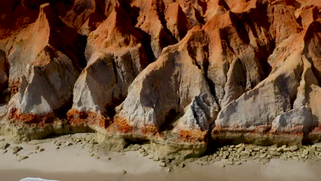 Aerial-view-of-the-cliffs-with-a-person-walking-along-the-beach,-Morro-Branco,-Ceara,-Fortaleza