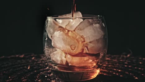 Liquid-pouring-into-a-spinning-clear-glass-with-ice-inside-it