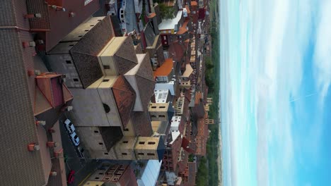 Vertical-Aerial-Drone-Shot-of-Riaño-in-Picos-de-Europa,-Spain,-with-Cloudy-Skies,-City-Center,-Mountain-Cliffs,-and-Lush-Green-Trees